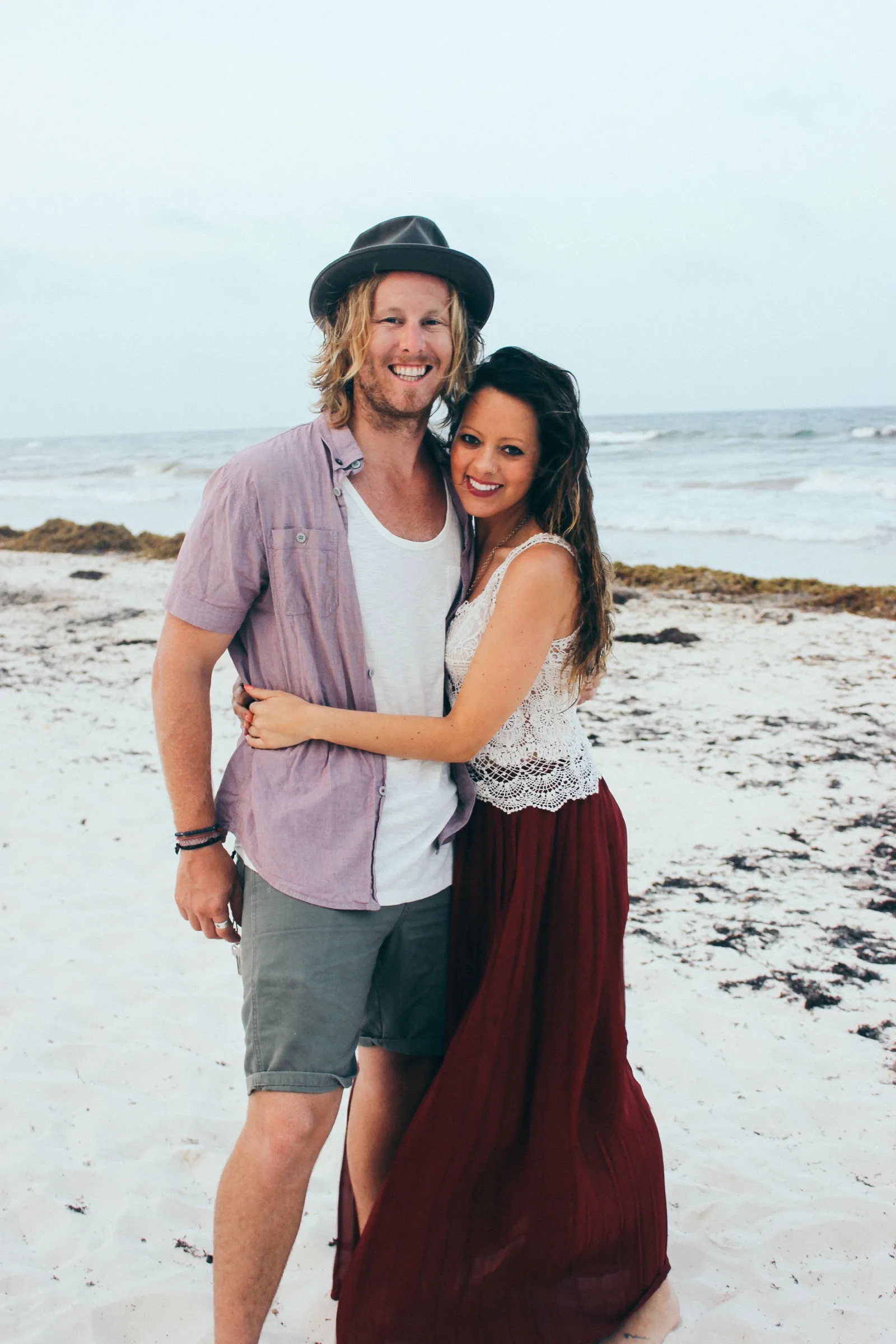 Jamey and Melissa embracing on a Tulum beach, jungle behind them