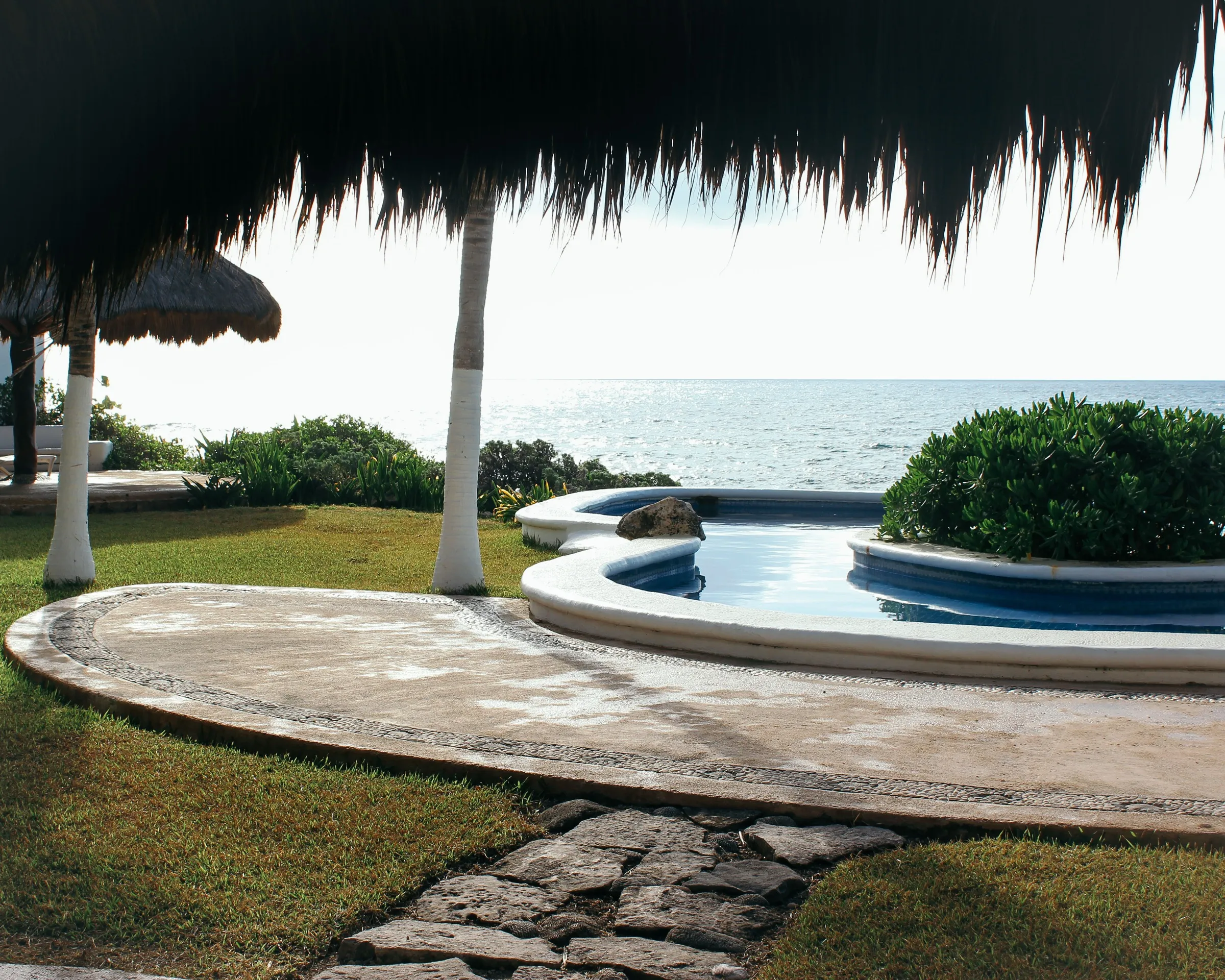 A thatched palapa over glassy turquoise Caribbean water in Akumal