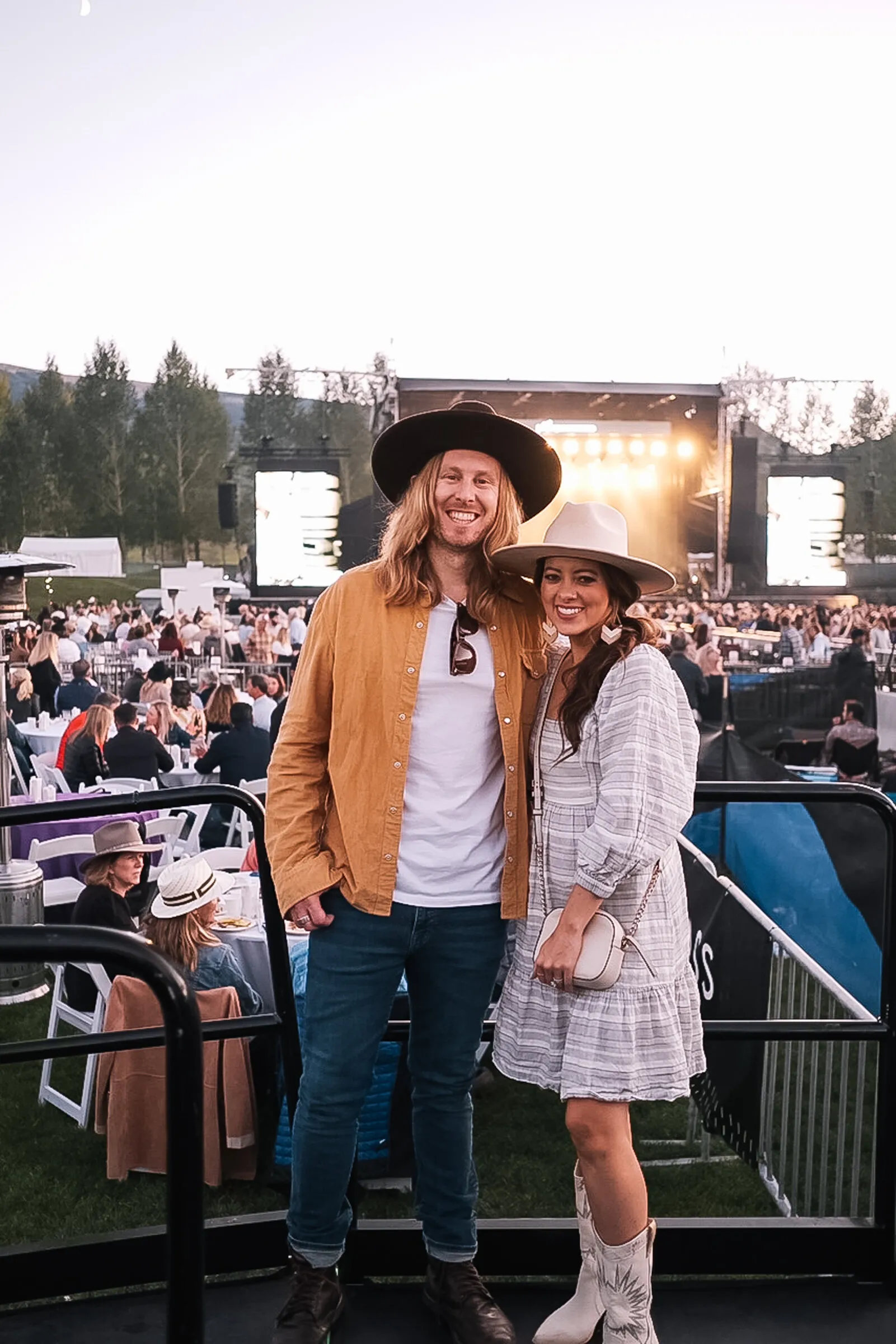 A couple in cowboy hats at the Jazz Aspen Snowmass festival, the stage lit up behind them