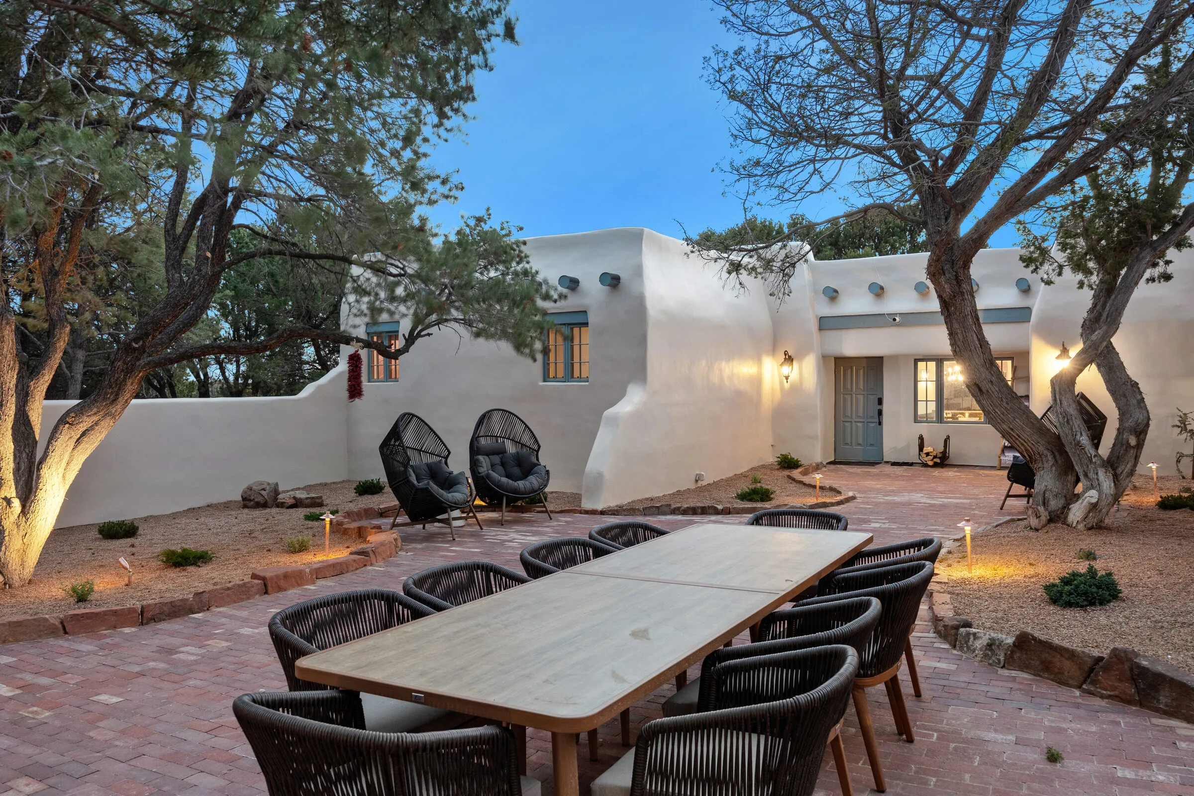 The long alfresco dining table at dusk, every window glowing behind it