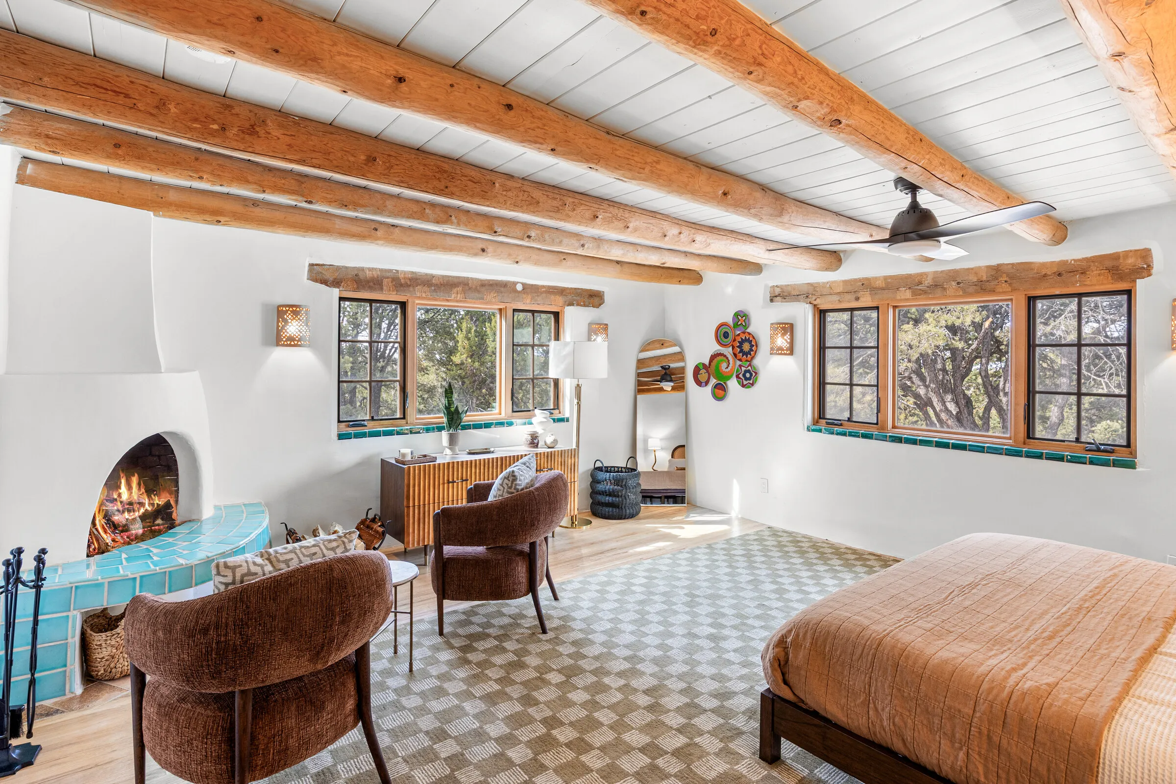 The master suite at Casa de Ice — turquoise-tiled kiva fireplace, viga ceiling, checkered rug
