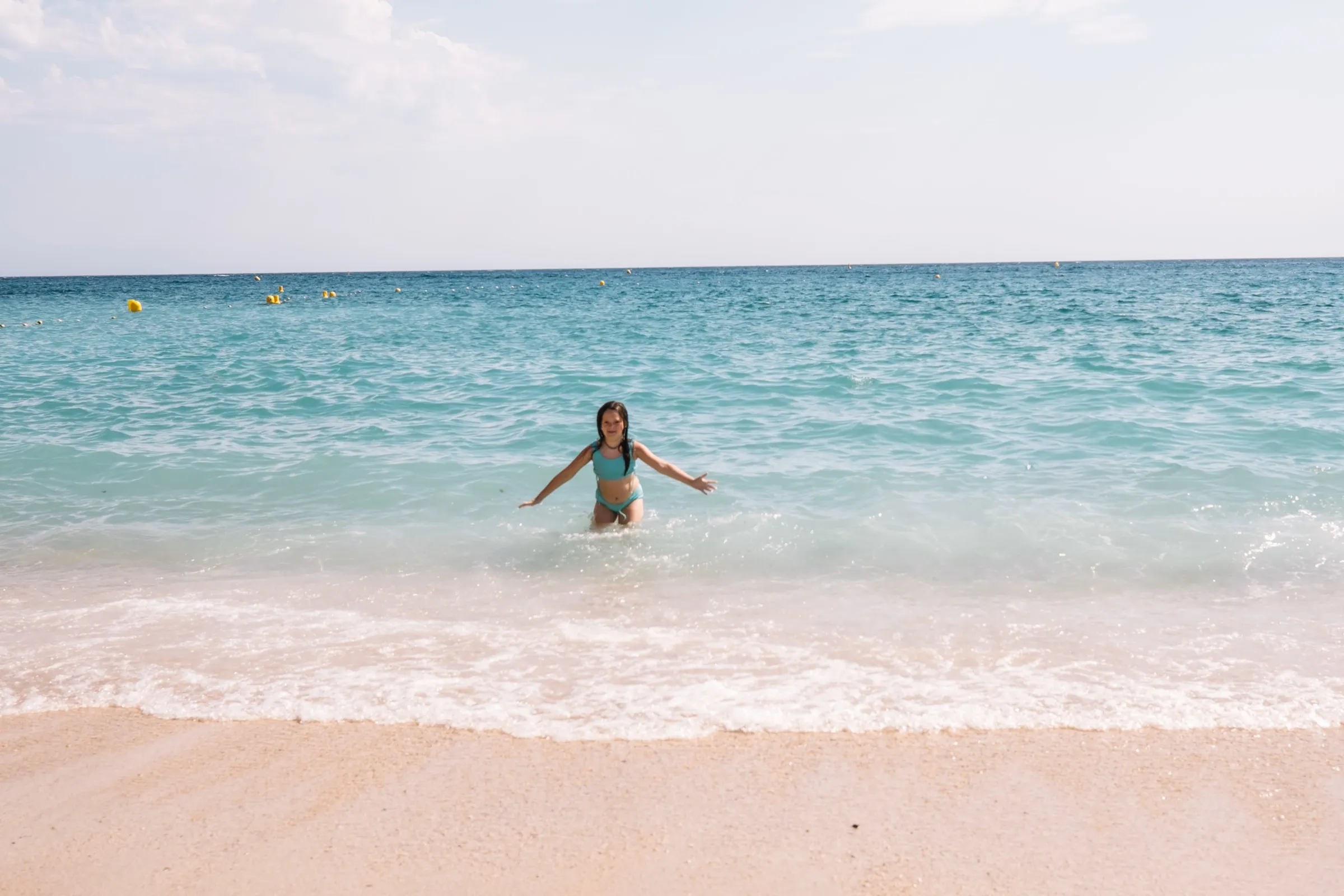 One of the girls swimming in the clear turquoise shallows