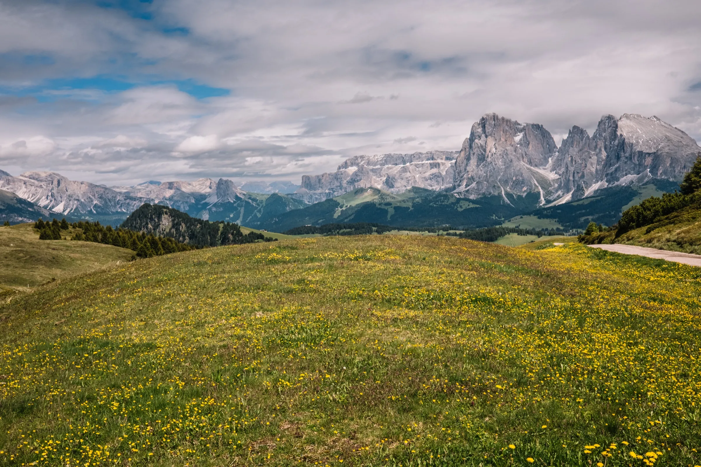 A small figure in a vast Dolomites meadow under the peaks