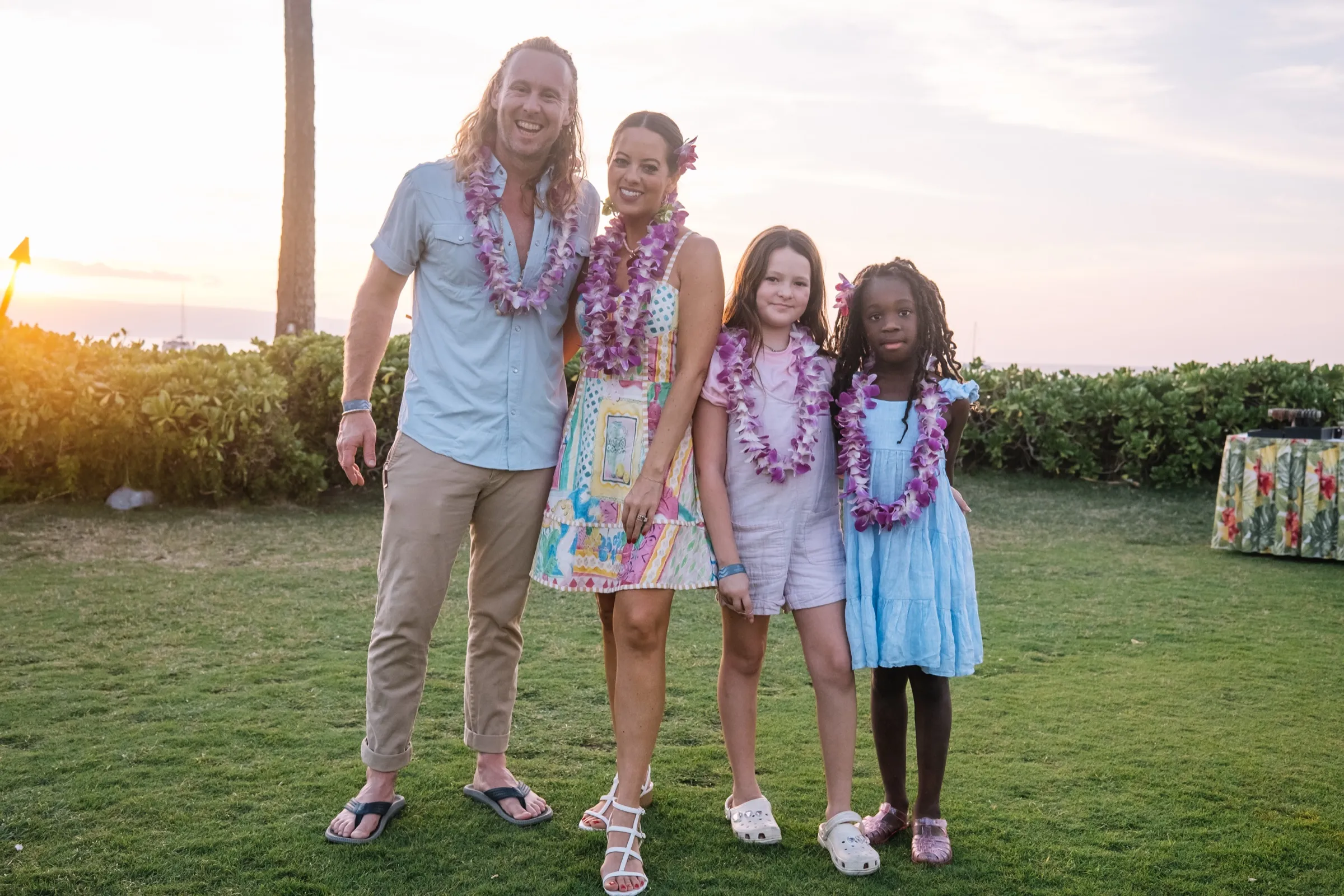 The whole Ice family on a lawn at golden hour, wearing leis