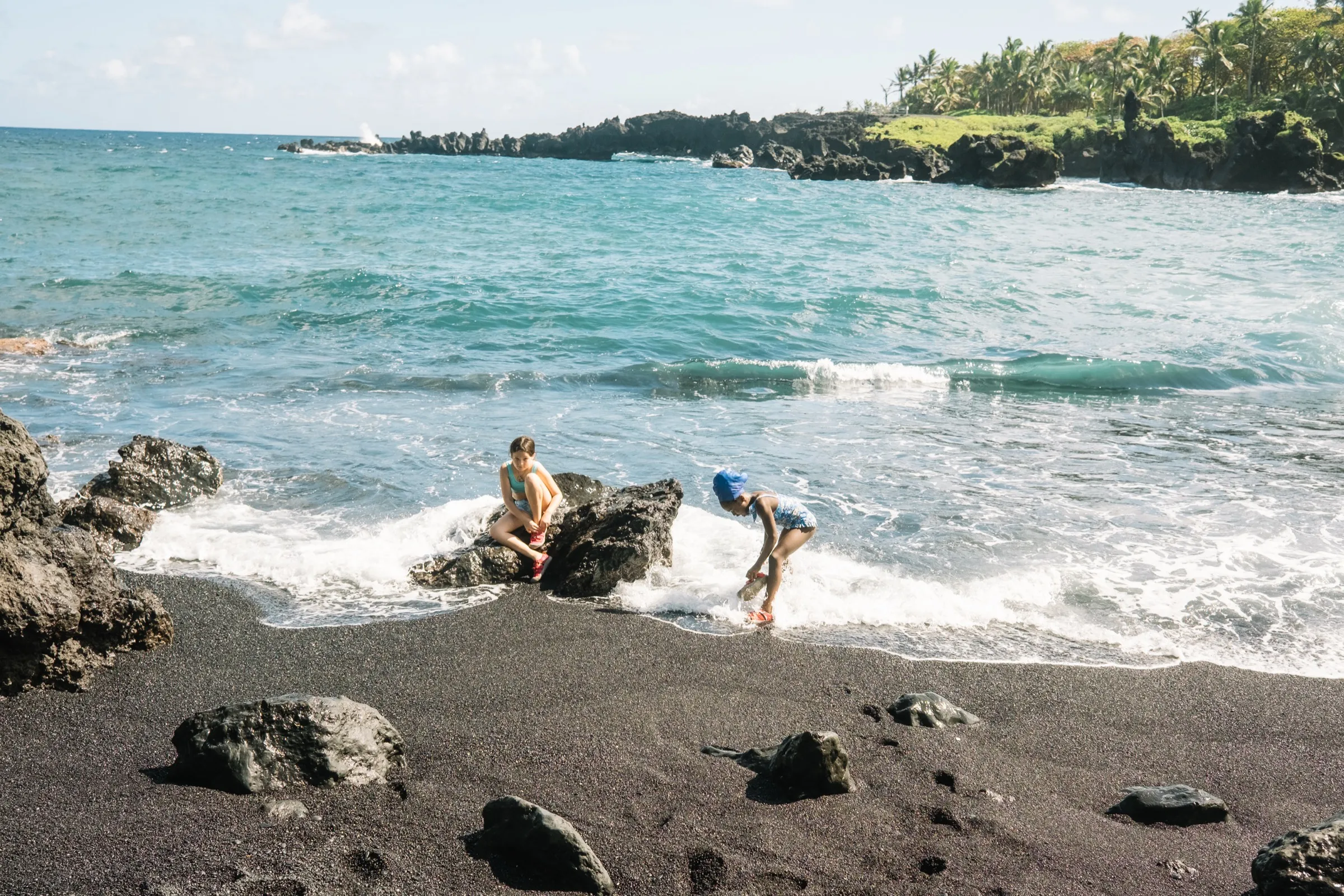 The girls scrambling the black-sand rocks at Wai'ānapanapa — what the points pay for