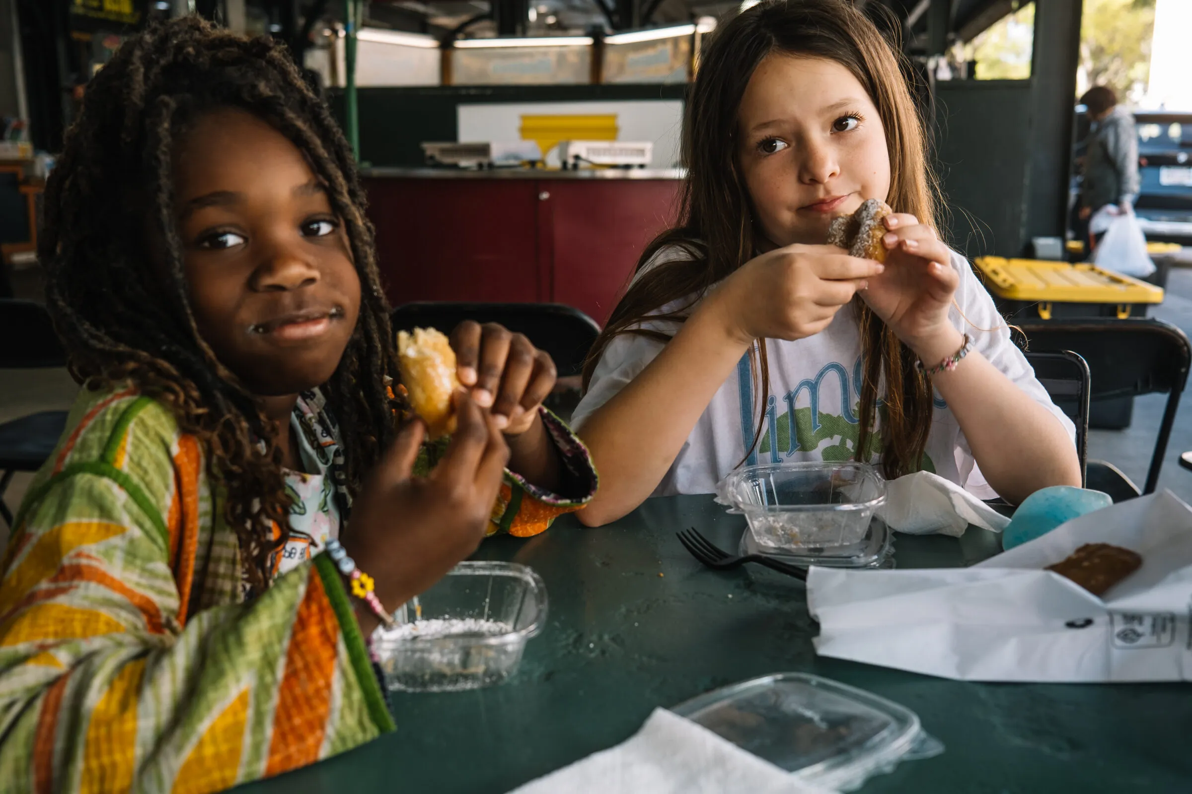 The girls eating at a shaded French Quarter courtyard lunch table